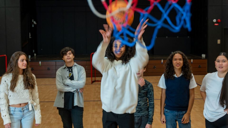 Ungdomar som spelar basket i en stor lokal