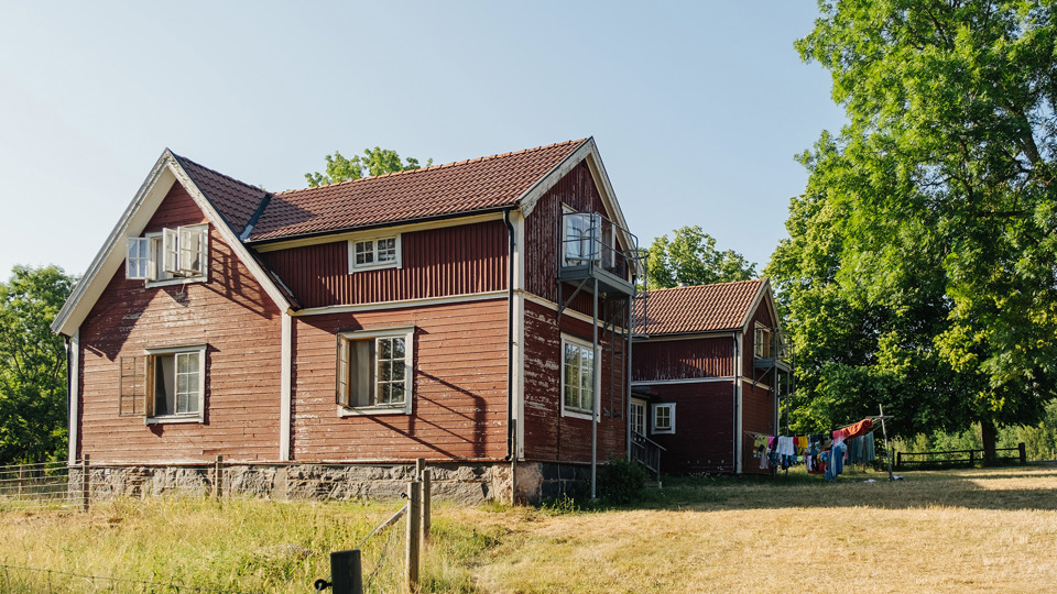 Stora röda trähus i en trädgård med gräs och träd.