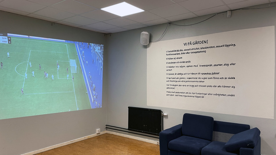 Spelrum med soffa och FIFA-spel som projiceras på en stor vägg