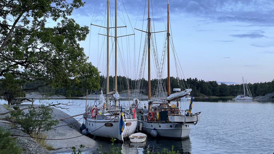 Två segelbåtar ligger förtöjda vid en klippa.