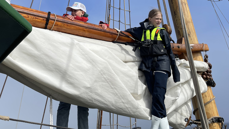 Två barn står vid masten på segelfartyget Shamrock.