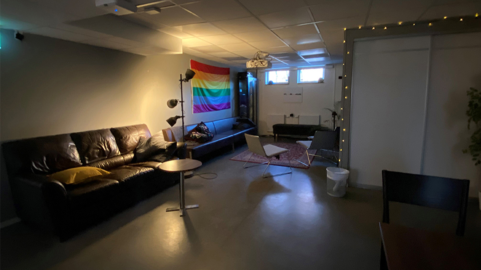 Soffhörna med prideflagga på väggen.