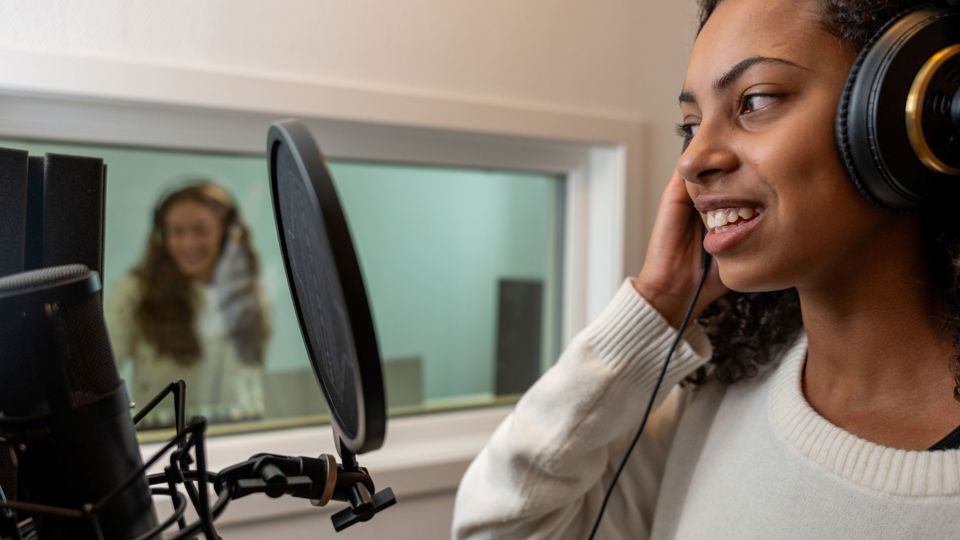 Glad tjej i musikstudio med hörlurar på sig