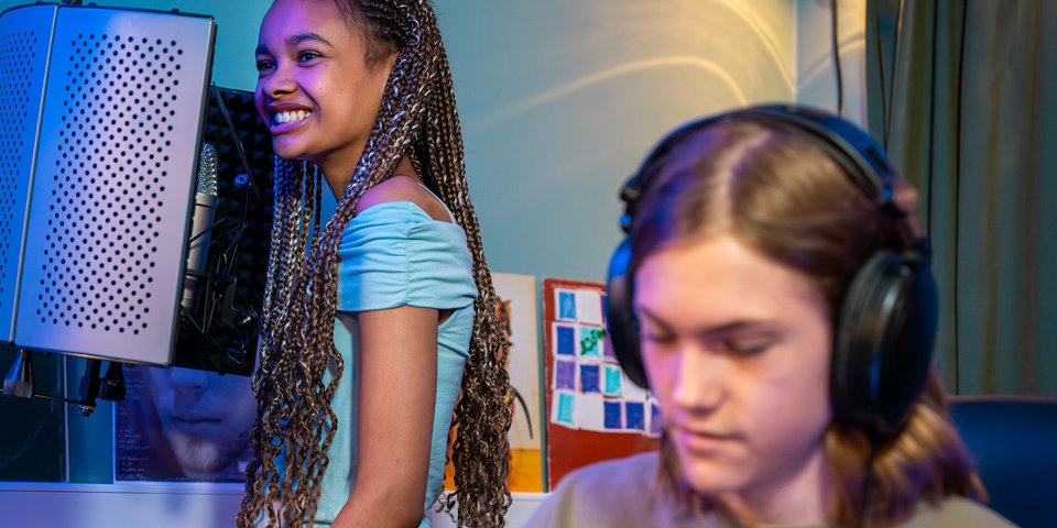 En kille och en tjej som spelar in musik på en fritidsgård. 