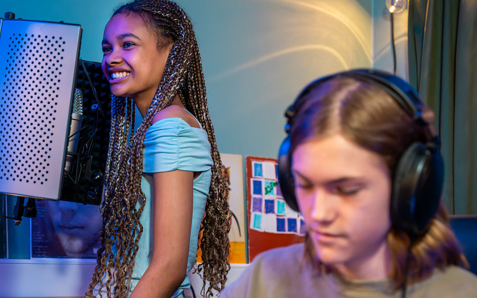 En kille och en tjej som spelar in musik på en fritidsgård. 