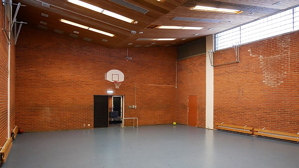 Bild på idrottshallen. Röd tegel längs väggarna och basketkorgar uppsatta.