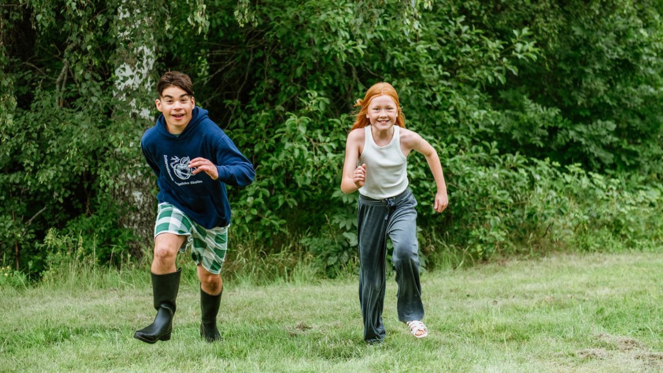 Två springande barn på en gräsmatta.